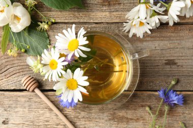 Cam bardakta Aromatik bitkisel çay, çiçekler ve ahşap masa, düz yatıyordu.