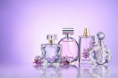 Ayna yüzeyindeki parfüm şişeleri ve leylak çiçekleri menekşe eğimli arka plan, metin için boşluk