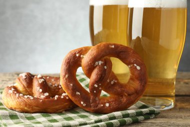 Lezzetli krakerler ve bira bardakları ahşap masada gri arka planda, yakın plan