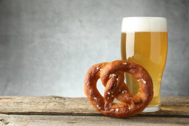 Lezzetli kraker ve bir bardak bira ahşap masada, arka planda gri, yakın plan. Metin için boşluk