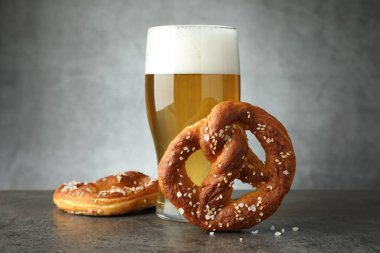 Lezzetli krakerler ve koyu dokulu masada bir bardak bira. Gri arka planda, yakın planda.