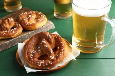 Lezzetli krakerler ve biralar yeşil ahşap masada, yakın plan.