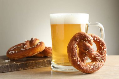 Lezzetli krakerler ve bir bardak bira ahşap masada, gri arka planda, yakın planda.