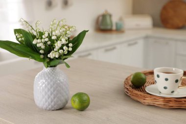 Vazodaki güzel zambak, limon ve çay, mutfaktaki ahşap masada, yakın plan.