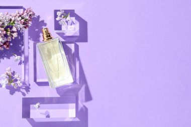 Düz kompozisyon, mor arka planda parfüm şişesi ve leylak çiçekleri vardı. Metin için boşluk