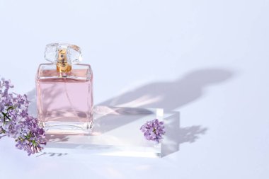 Açık gri arka planda bir şişe parfüm ve leylak çiçeği, yakın plan. Metin için boşluk