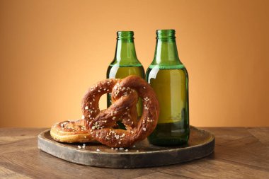 Lezzetli krakerler ve bira şişeleri ahşap masa üzerinde bej renkli gradyan arka plan, yakın çekim