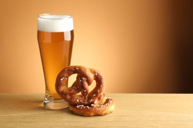 Lezzetli krakerler ve ahşap masada bir bardak bira bej renkli arka planda, yakın plan. Metin için boşluk