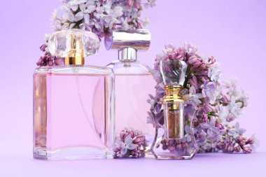 Parfümlü şişeler ve mor arka planda leylak çiçekleri, yakın plan.