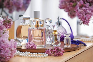 Parfümlü şişeler ve tuvalet masasında leylak çiçekleri, yakın plan.