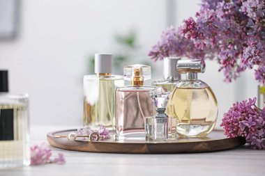 Beyaz ahşap masada parfüm şişeleri ve leylak çiçekleri.