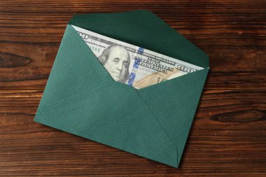 Para bonusu. Tahta masanın üstünde dolar banknotuyla zarf, üst manzara.