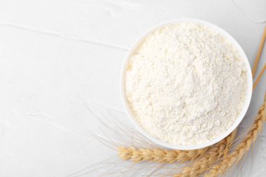 Buğday unu kasede ve çiviler beyaz masada, düz yerde. Metin için boşluk