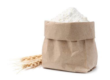 Kese kağıdında buğday unu ve beyaz arka planda çiviler.