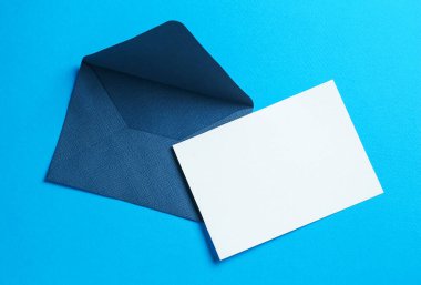 Açık mavi arka planda boş davetiye ve zarf, üst manzara. Tasarım için boşluk