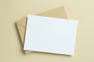 Bej arka planda boş davetiye ve zarf, üst manzara. Tasarım için boşluk