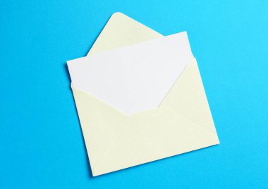 Açık mavi arka planda boş davetiye ve zarf, üst manzara. Tasarım için boşluk