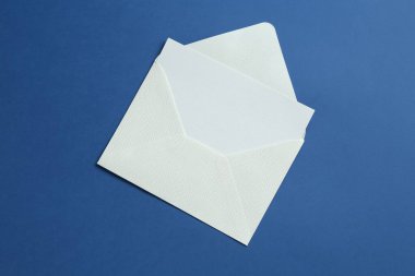 Mavi arka planda boş davetiye ve zarf, üst manzara. Tasarım için boşluk