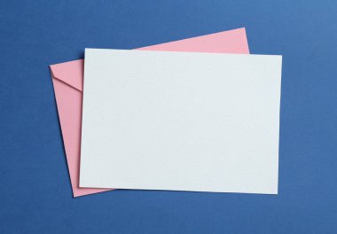 Mavi arka planda boş davetiye ve zarf, üst manzara. Tasarım için boşluk