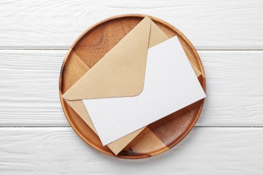 Boş davetiye kartı, zarf ve tepsi beyaz ahşap masa, üst görünüm