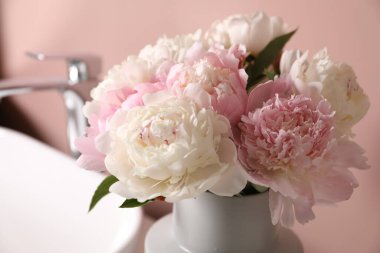 Vazodaki güzel şakayıklar ve lavabo pembe duvarın yanında, yakın plan.