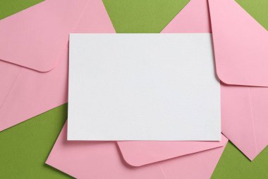 Boş davetiye kartı ve yeşil arka planda zarflar. Tasarım için boşluk