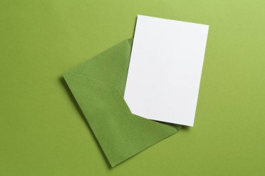 Yeşil arka planda boş davetiye ve zarf, üst manzara. Tasarım için boşluk