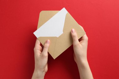 Kırmızı arkaplanda boş davetiye kartı olan kadın, üst görünüm