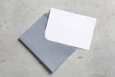 Açık gri masadaki boş davetiye ve zarf, üst manzara. Tasarım için boşluk