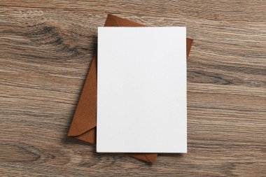 Boş davetiye kartı ve zarf ahşap masanın üstünde, üst tarafta. Tasarım için boşluk