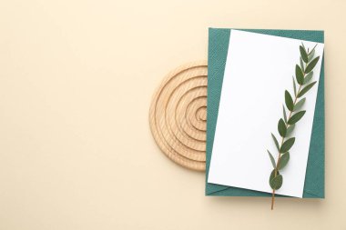Boş davetiye kartı, zarf ve bej arka planda yeşil dal, üst manzara. Metin için boşluk