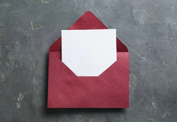 Boş davetiye kartı ve zarf gri masada, üst tarafta. Tasarım için boşluk