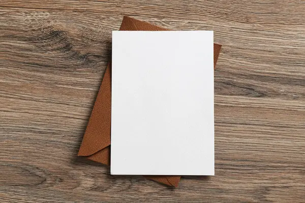 Boş davetiye kartı ve zarf ahşap masanın üstünde, üst tarafta. Tasarım için boşluk