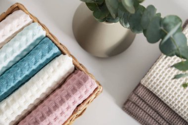 Banyodaki beyaz masada dalları olan temiz waffle havluları ve vazo, düz uzanmış.