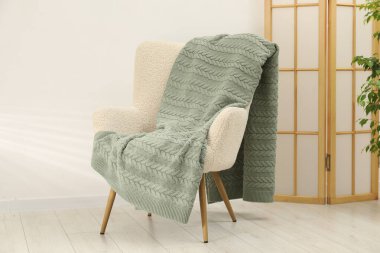 Yeşil yün battaniyeli rahat bir koltuk.