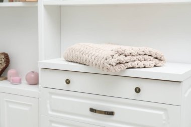 Beyaz çekmecelerin üzerindeki yün battaniye kapalı, yakın plan.