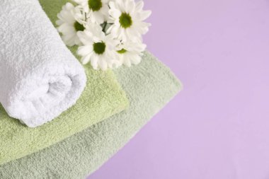 Yumuşak havlular ve mor arka planda kasımpatı çiçekleri, manzaranın üstünde. Metin için boşluk