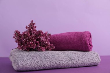 Renkli arka planda yumuşak havlular ve leylak çiçekleri, yakın plan