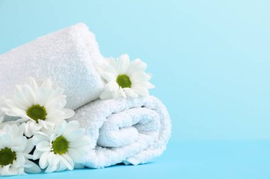 Yumuşak havlular ve açık mavi arka planda kasımpatı çiçekleri, yakın plan. Metin için boşluk