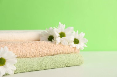 Yumuşak havlular ve yeşil arka planda kasımpatı çiçekleri, yakın plan. Metin için boşluk