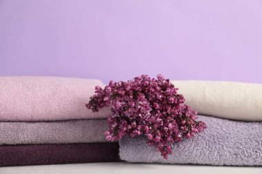 Beyaz masadaki yumuşak havlular ve leylak çiçekleri menekşe arka planına karşı, yakın plan