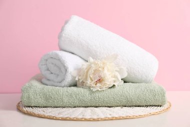 Masada pembe arka planda yumuşak havlu ve şakayık çiçeği yığını