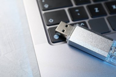 Flaş bellek ve laptop açık gri masada, yakın plan.