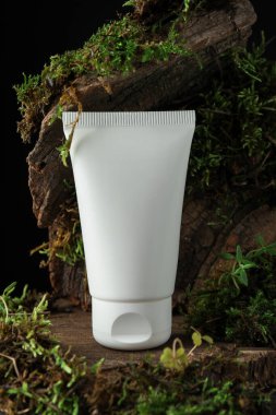 Ağaç kabuğunda bitkilerle birlikte nemlendirici vücut kremi, yakın plan.