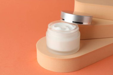 Turuncu arka plandaki kavanozda nemlendirici vücut kremi sunumu, yakın plan. Metin için boşluk