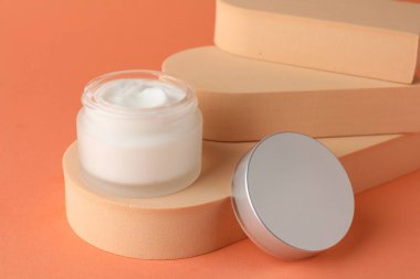 Turuncu arka plandaki kavanozda nemlendirici vücut kremi sunumu, yakın plan.