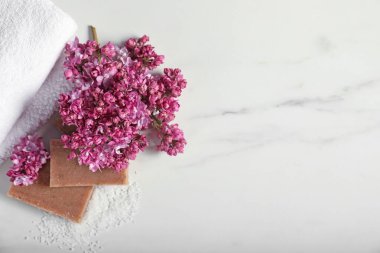Sabun çubukları, deniz tuzu ve leylak çiçekleri beyaz mermer masada, düz yerde. Metin için boşluk
