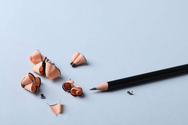 Keskin grafit kalem ve açık gri arka planda talaş, yakın plan. Metin için boşluk