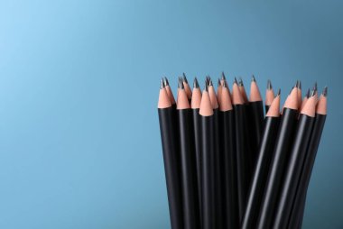 Açık mavi arka planda birçok keskin grafit kalem, yakın plan. Metin için boşluk