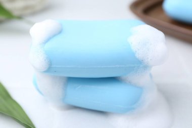 Beyaz masadaki köpüklü sabun çubukları, yakın plan.